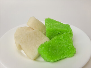 Jadah ketan (white) and wajik ketan (green), two traditional snacks from Indonesia. Made from sticky rice. On a white plate, isolated in white background