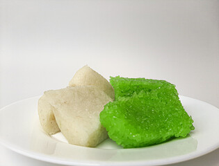 Jadah ketan (white) and wajik ketan (green), two traditional snacks from Indonesia. Made from sticky rice. On a white plate, isolated in white background