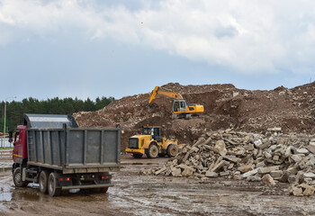 Excavator, dump truck and wheel loader at landfill for disposal of construction waste and concrete...