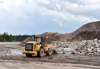 Front end loader and excavator at landfill for disposal of construction waste. Gravel and concrete crushing. Recycling old concrete and asphalt from demolition. Salvaging, removal building materials