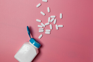 White medical pills and tablets spilling out of a drug bottle. Macro top 