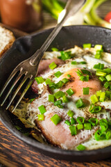 Fried eggs with ham on an old wooden background.