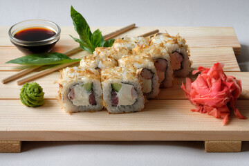 Japanese sushi rolls named Favorite  with wasabi, soy sauce, basil leaves and marinated ginger. Tasty and artistic food for restaurant or cafe menu. Roll on wooden board. Paper textures on background.
