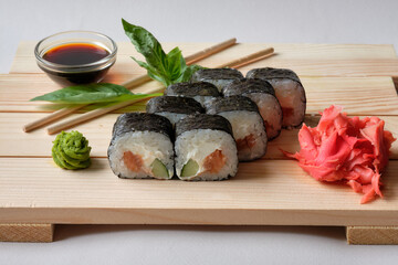 Japanese sushi rolls with Fish avocado,  cheese, wasabi, soy sauce, and marinated ginger. Tasty and artistic food for restaurant, cafe menu. Roll on wooden board.