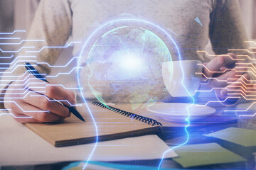 Double exposure of writing hand on background with brain hologram. Concept of learning.