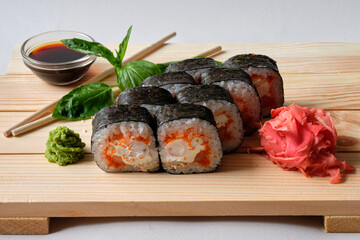 Japanese sushi rolls named Kunsei with cucumber, Salmon, eel, Snow crab, wasabi, soy sauce, basil leaves and marinated ginger. Tasty and artistic food for restaurant or cafe menu. Roll on wooden board