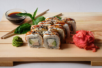 Japanese sushi rolls with Fish avocado,  cheese, wasabi, soy sauce, and marinated ginger. Tasty and artistic food for restaurant, cafe menu. Roll on wooden board