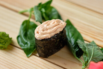 Japanese sushi with basil leaves on wooden table
