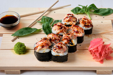 Japanese sushi rolls with Fish avocado,  cheese, wasabi, soy sauce, and marinated ginger. Tasty and artistic food for restaurant, cafe menu. Roll on wooden board.