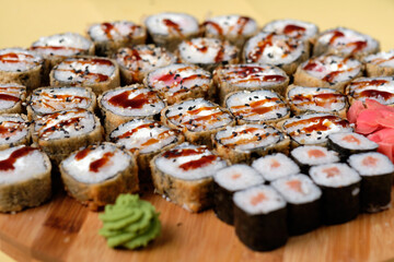 Fresh assorted Japanese sushi rolls with pickled ginger and wasabi on the wooden board. Restaurant or cafe menu images. Food photography. Top view.