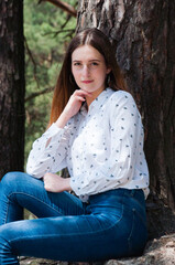 Obraz premium Very beautiful young woman in coniferous forest in summer in hot sunny weather