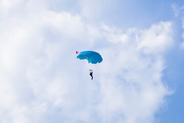 Skydiver and colorful parachute on the blue sky 