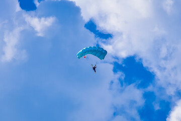 Skydiver and colorful parachute on the blue sky 