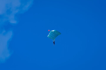 Skydiver and colorful parachute on the blue sky 