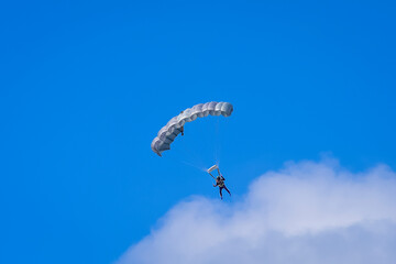 Obraz na płótnie Canvas Skydiver and colorful parachute on the blue sky 