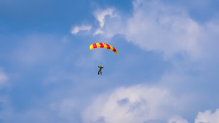 Skydiver and colorful parachute on the blue sky 