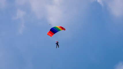 Skydiver and colorful parachute on the blue sky 