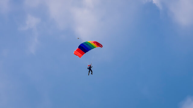 Skydiver and colorful parachute on the blue sky 