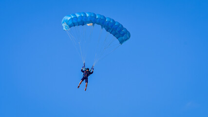 Naklejka na ściany i meble Skydiver and colorful parachute on the blue sky 