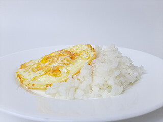 Fried egg or overcooked sunny side up, served with white rice, on a white plate, isolated in white background
