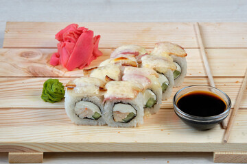 Japanese sushi rolls with baked cheese, avocado, bacon, wasabi, soy sauce and marinated ginger. Tasty and artistic food for restaurant or cafe menu. Roll on wooden board. look catalog to download.