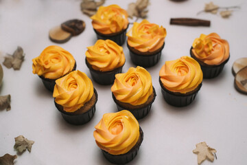 Autumn sweets, cupcakes on a table with dried leaves and pumpkin. Homemade treats