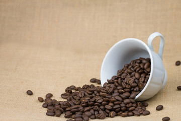Coffee beans in a white coffee cup on the side And the glass resting on a brown background
