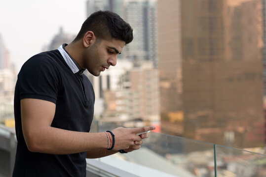 Young handsome Indian man using phone in the city