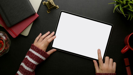 Female hand touching on mock-up digital tablet on feminine stylish worktable with supplies and decorations