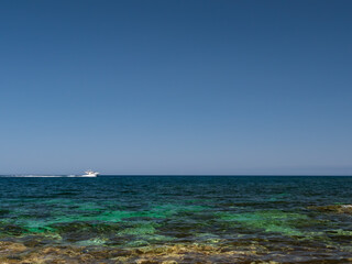 Fototapeta na wymiar Speed boat on horizon of the Mediterranean sea seen from the shore on sunny day with clear skies