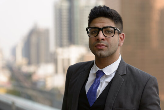 Young handsome Indian businessman with eyeglasses in the city