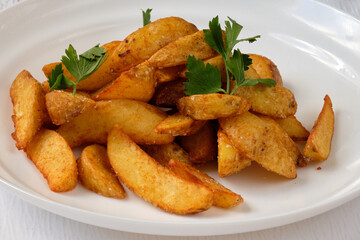 Fried potatoes with parsley on white plate. Image for cafe or bistro menu.