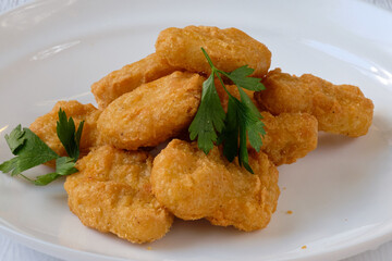 fried chicken nuggets with parsley on the white plate