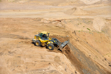 Fototapeta na wymiar Front end loader has been recovering the landscape around the open pit. Process of restoring land. Mine reclamation occurs once mining sand is completed