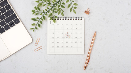 Calendar with rose gold pen on white table