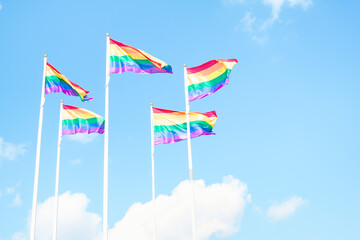 LGBT flags waving on sky background with clouds, horizontal, copy space