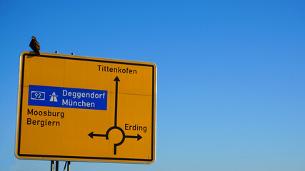 Straßenschild zum Kreisverkehr Erding-Tittenkofen-Deggendorf mit Vogel
