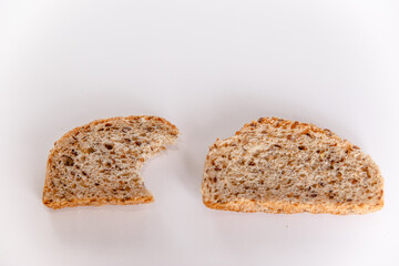 A bitten piece of bread with cereals on a white background