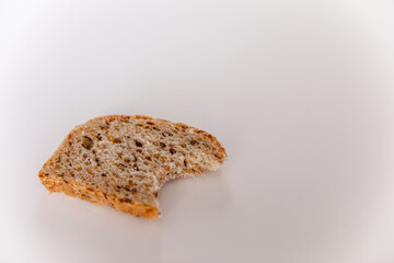 A bitten piece of bread with cereals on a white background