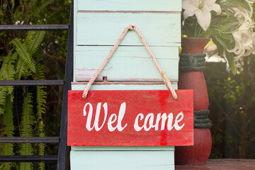 Welcome message label, white characters On a red background Hang it with a rope Beside the greenwood wall