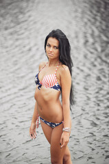 Young beautiful woman with beautiful body with american flag on the beach