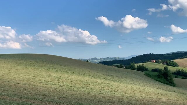 Beautiful meadows and fields on a sunny day on the soft hills of the Colli Piacentini, near Piacenza, Emilia Romagna, Italy. Clouds shadows moving fast on the ground