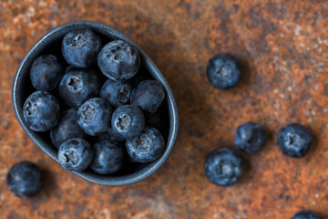Blueberries in a small bowl on a red old background