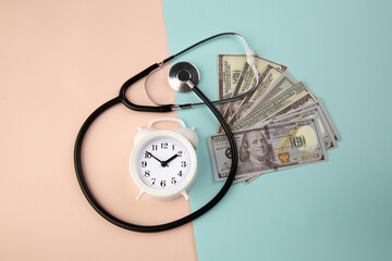 Money dollar with alarm clock and a stethoscope - expensive cost of healthcare or financing medicine.