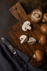 Fresh champignon mushrooms on a cutting board and on a black background