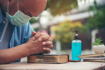 Prayer and bible concept. Asian senior man wear medical mask praying, hope for peace the world and free from coronavirus, Hand in hand together, believes and faith in christian religion at church.