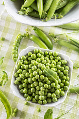 Green raw peas and pods in pocelain bow isolated on wooden table