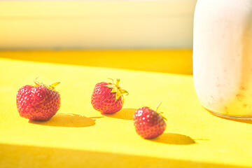 ripe strawberries on a yellow background. milkshake in a jar