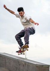 Young athletic male doing tricks with a skateboard at a skate park during daytime