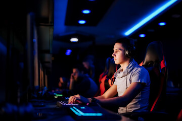Naklejka na ściany i meble Online gaming concept. Portrait of a gamer playing online video game at cybercafe.